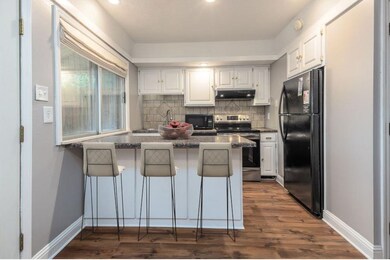 Kitchen with white cabinetry, a breakfast bar, kit