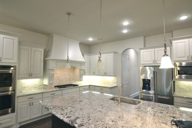 Kitchen has Huge Granite island with overhang for Stool-seating at the island, SS sink, drop-lights over the Island, 50 drawers and Cabinets, excellent millwork in the lighted  Vent hood with corbels, a high-Quality Gas Cooktop, Built-in Dual electric ovens and Microwave, and (not shown in this photo, the SS Dishwasher on other side of the Huge Granite Island.