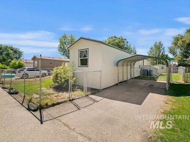 View of front facade with a gate, a detached carport, and driveway