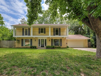 View of front of home featuring a balcony, a garage, driveway, and brick siding