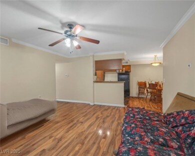 Living room with crown molding, wood finished floo
