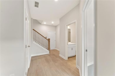 Corridor featuring light wood-type flooring, stairway, and recessed lighting