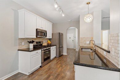 Kitchen has gorgeous laminate hardwood floors, granite countertops, white cabinets with hardware, stainless steel appliances, upgraded stove, travertine backsplash, spice rack in pantry, and awesome lighting.