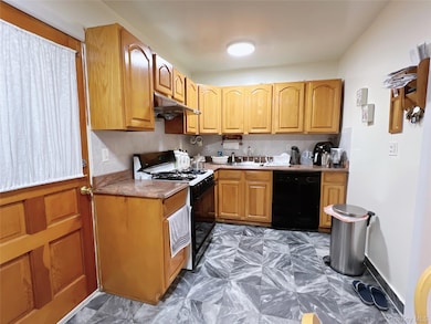 Kitchen featuring black appliances, under cabinet range hood, and brown cabinetry