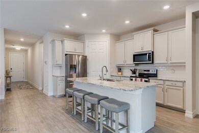 Kitchen featuring appliances with stainless steel finishes, recessed lighting, decorative backsplash, light stone countertops, and a kitchen bar