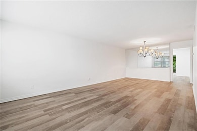 Empty room with a notable chandelier and wood-type flooring