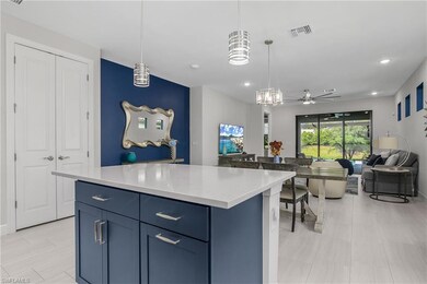 Kitchen featuring blue cabinetry, light stone counters, a center island, open floor plan, and a ceiling fan