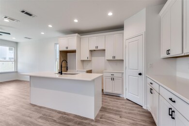 Kitchen with white cabinetry, sink, and an island 