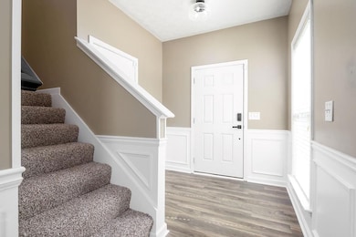 Foyer entrance with stairs, a wainscoted wall, woo