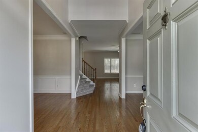 Entryway featuring dark wood-style floors, crown molding, stairway, wainscoting, and a decorative wall