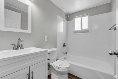 Full bath with washtub / shower combination, vanity, and a textured wall