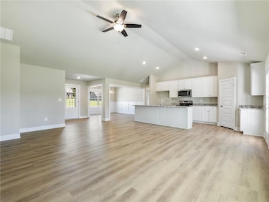 Unfurnished living room featuring high vaulted ceiling, ceiling fan, baseboards, a sink, and recessed lighting