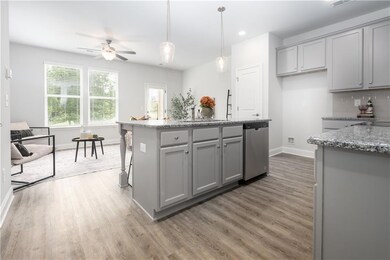 Kitchen featuring gray cabinets, light stone counters, hanging light fixtures, wood finished floors, and recessed lighting