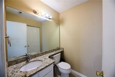 Bathroom with toilet, vanity, and baseboards