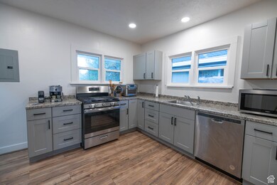 Kitchen featuring gray cabinetry, appliances with stainless steel finishes, electric panel, dark wood-style floors, and recessed lighting