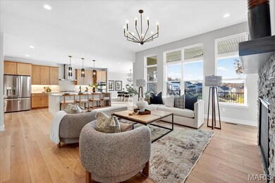 Great room with a stone fireplace, a chandelier, light wood-style floors, and recessed lighting