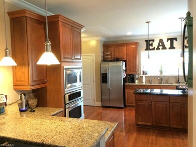 Custom cabinetry, island with cooktop, granite counters and stainless steel appliances