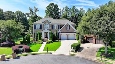 Colonial home featuring driveway, a front lawn, and stone siding