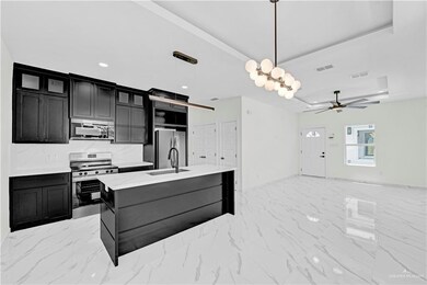 Kitchen with dark cabinets, a tray ceiling, appliances with stainless steel finishes, marble finish floor, and a sink