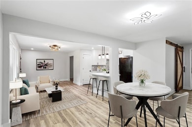 Dining space featuring baseboards, a barn door, li