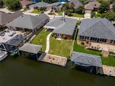 Aerial view of house in middle.  It has two chair with red pillows on the deck.  Plenty of yard space as you can see.