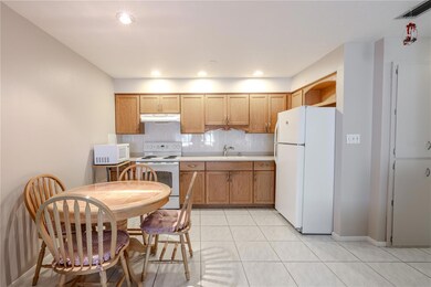View of the dining area just off the kitchen, featuring warm wood cabinets and sleek Corian countertops. The space is bright and inviting, offering a seamless connection between cooking and dining, perfect for everyday meals or entertaining guests.