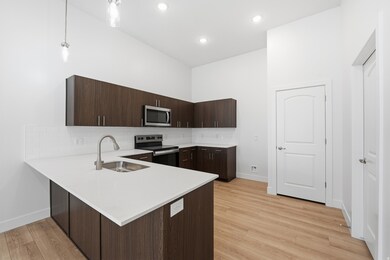 Elevated kitchen with quartz counter, tile backsplash, and stainless steel appliances.