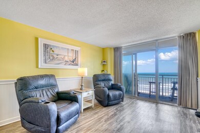 Sitting room with a textured ceiling, wood finished floors, a water view, and a wainscoted wall