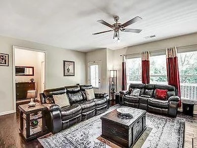 Living area featuring dark wood-style floors, plenty of natural light, and ceiling fan