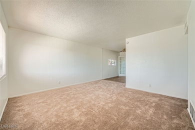 Carpeted spare room with visible vents, a textured
