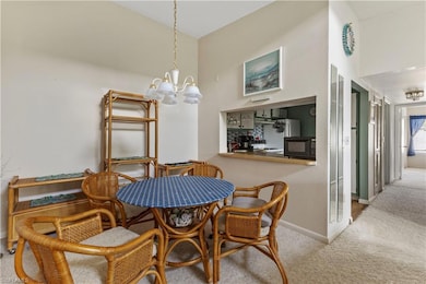 Carpeted dining room featuring a chandelier and baseboards
