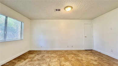 Spare room with a textured ceiling, light tile pat
