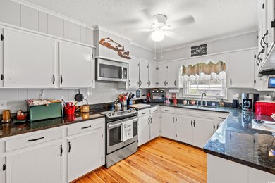 Kitchen with appliances with stainless steel finishes, crown molding, a textured ceiling, white cabinetry, and a ceiling fan