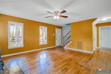 Unfurnished living room featuring light wood-style flooring, stairway, a textured ceiling, and a ceiling fan