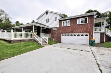 A view of the back of the home with the 2 car integral garage, the side porch which is off of the kitchen and the beautiful back patio with access through the game room.