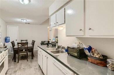 Kitchen with white appliances, a sink, light wood