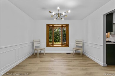 Sitting room with light wood finished floors, a chandelier, a wainscoted wall, and a decorative wall