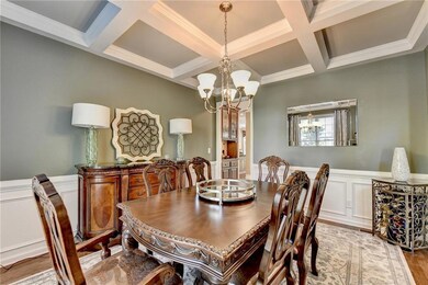 Dining room featuring a decorative wall, wainscoting, crown molding, a chandelier, and light wood-type flooring