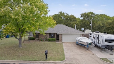 Ranch-style home featuring brick siding, a front lawn, concrete driveway, and a shingled roof
