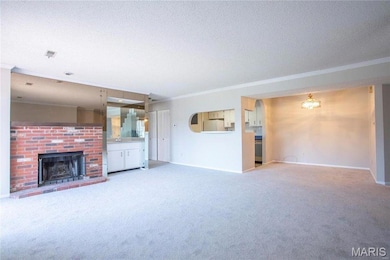 Unfurnished living room featuring crown molding, a fireplace, light carpet, and a textured ceiling