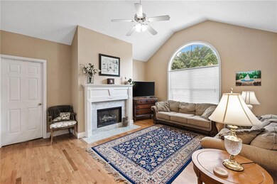 Living room featuring ceiling fan, light wood-type flooring, lofted ceiling, and a premium fireplace