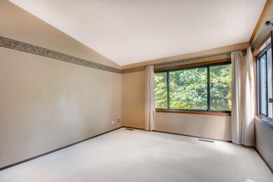 Large windows overlook a green space with mature t