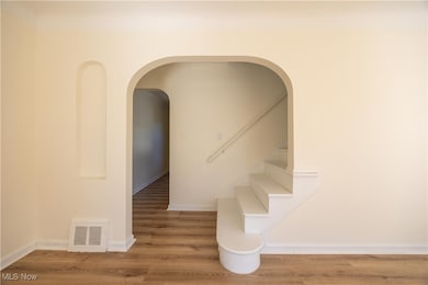 Stairway featuring wood finished floors and arched walkways