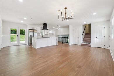 Unfurnished living room featuring recessed lighting, light wood finished floors, a chandelier, and stairway