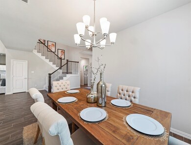 Beautiful dining room in this breathtaking home - featuring a stunning chandelier, wood-look tile floors, and a wonderful layout opening into the kitchen and living room!