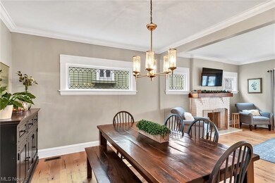 Dining room featuring crown molding, a notable chandelier, light hardwood / wood-style flooring, and a brick fireplace