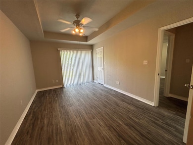 Empty room with a tray ceiling, baseboards, dark 