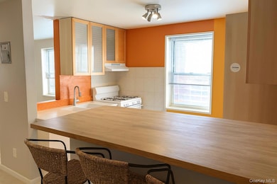 Kitchen with gas range gas stove, under cabinet range hood, and a kitchen breakfast bar. AI enhanced.