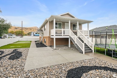 View of front of home with a trampoline, a fenced backyard, covered porch, and stairway