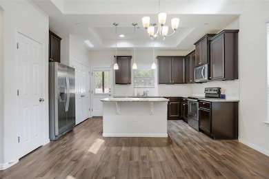 Kitchen with a tray ceiling, dark brown cabinetry